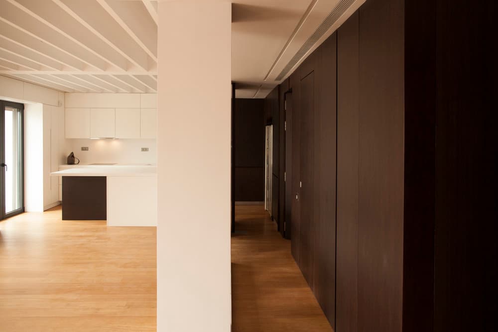 Dark timber wall dividing kitchen and private corridor