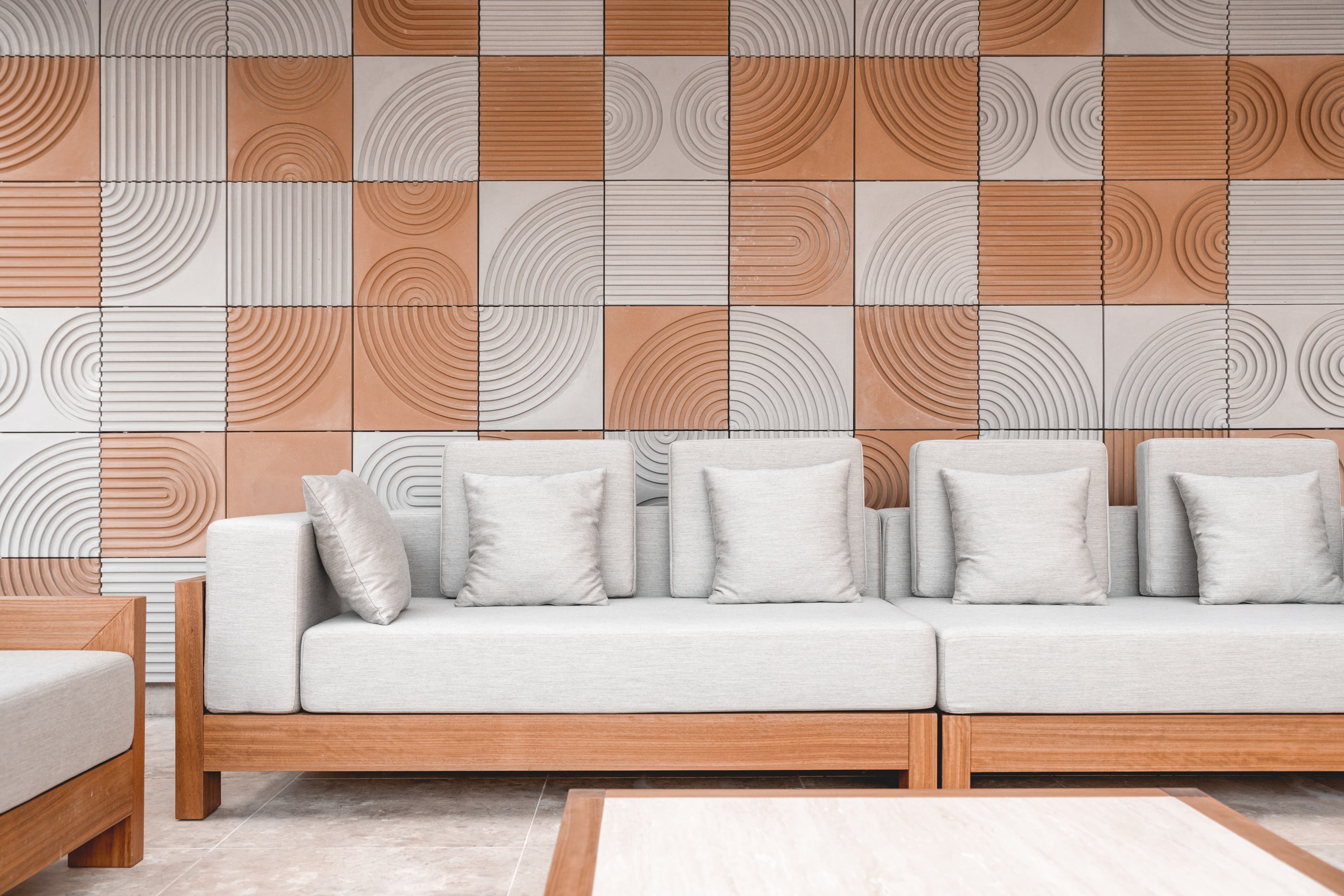 Outdoor sofa against the labyrinth-patterned GRC panels