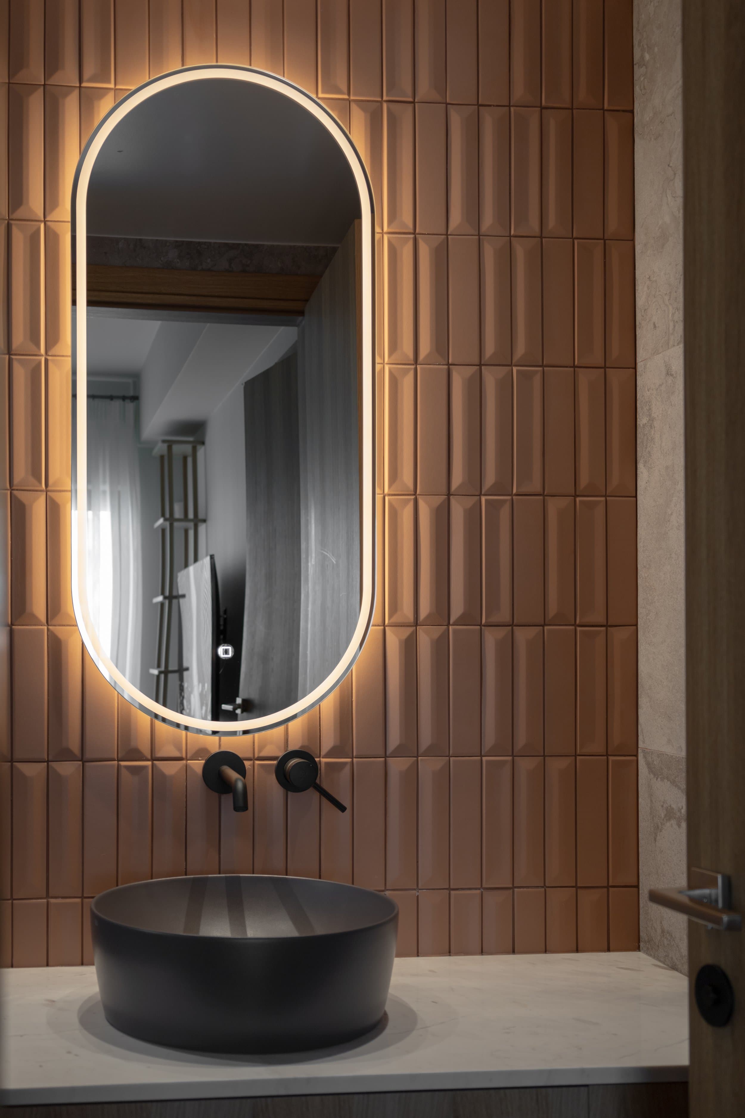 Guest bathroom with terracotta tiles and backlit oval mirror