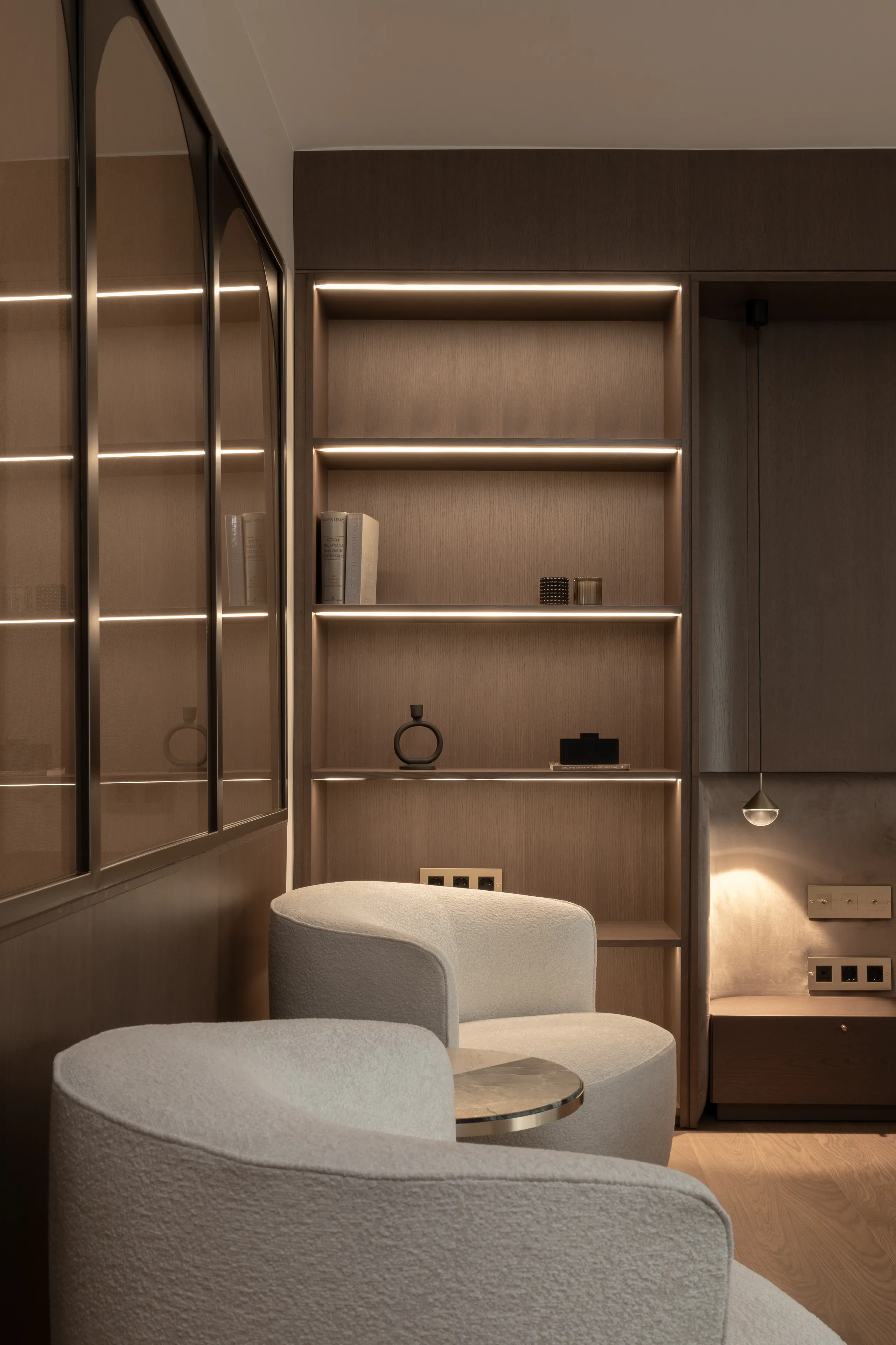 Reading corner with curved armchairs and lit shelving