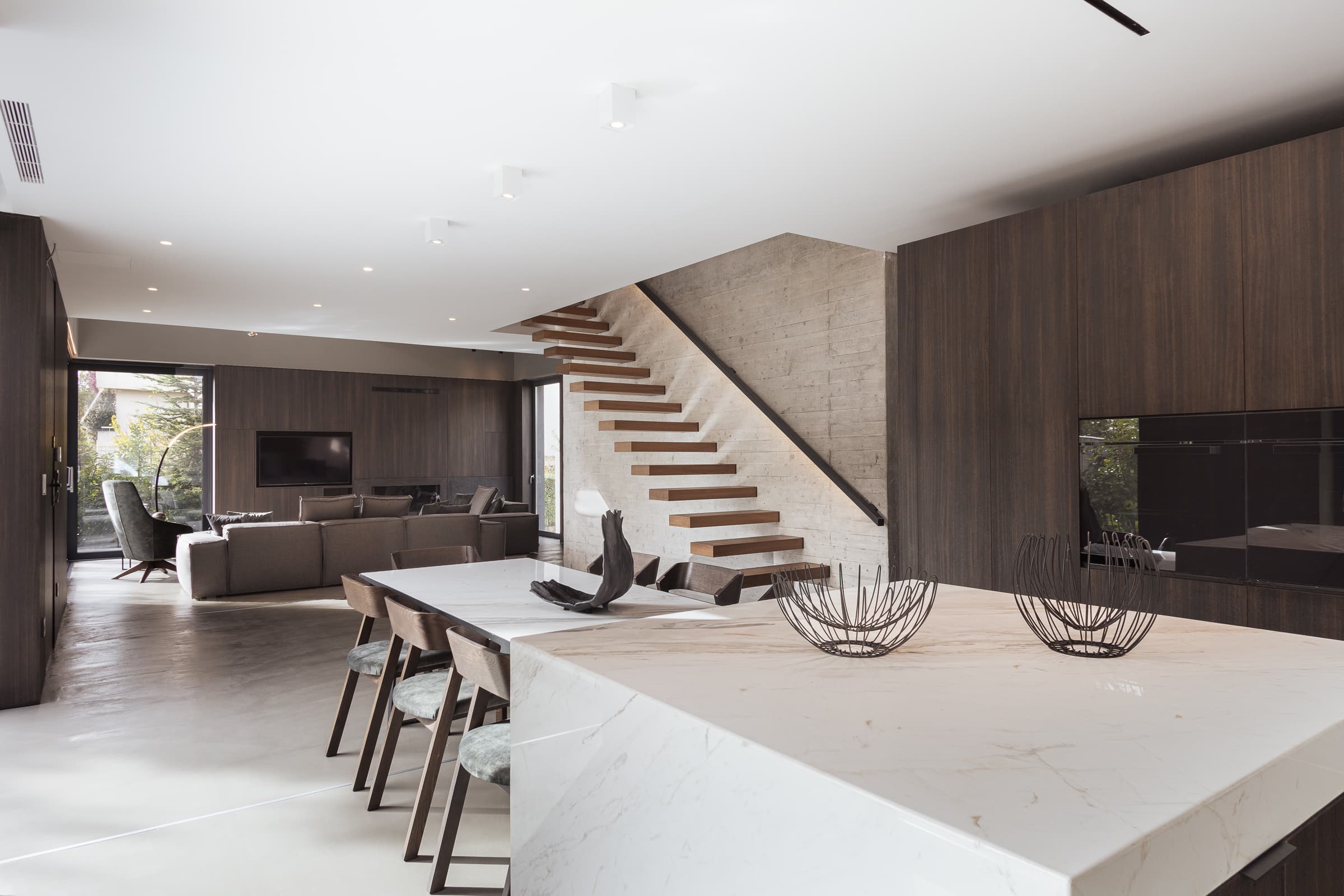 Open-plan living and dining along the board-formed concrete wall