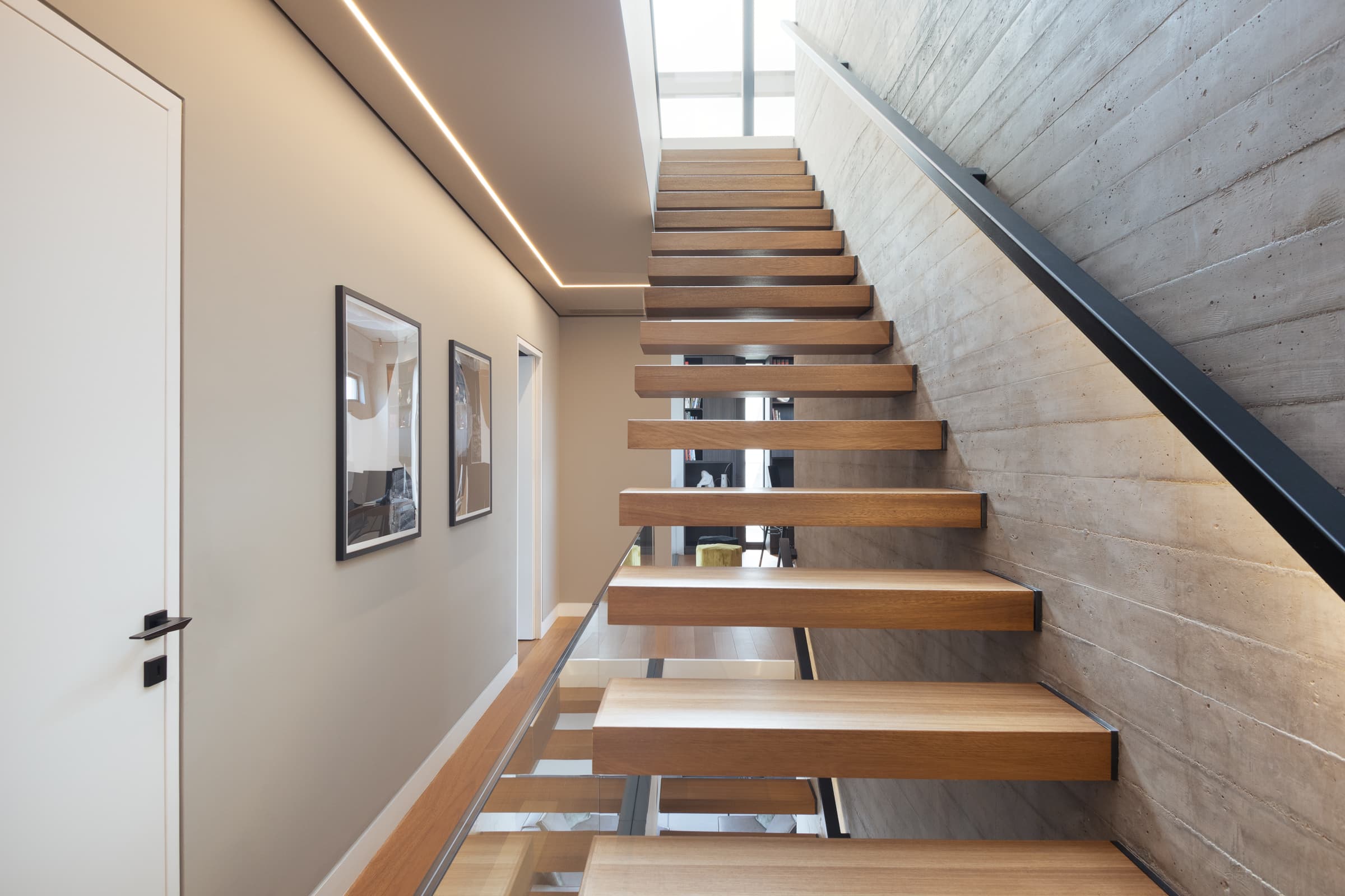 Floating timber staircase against the board-formed concrete wall